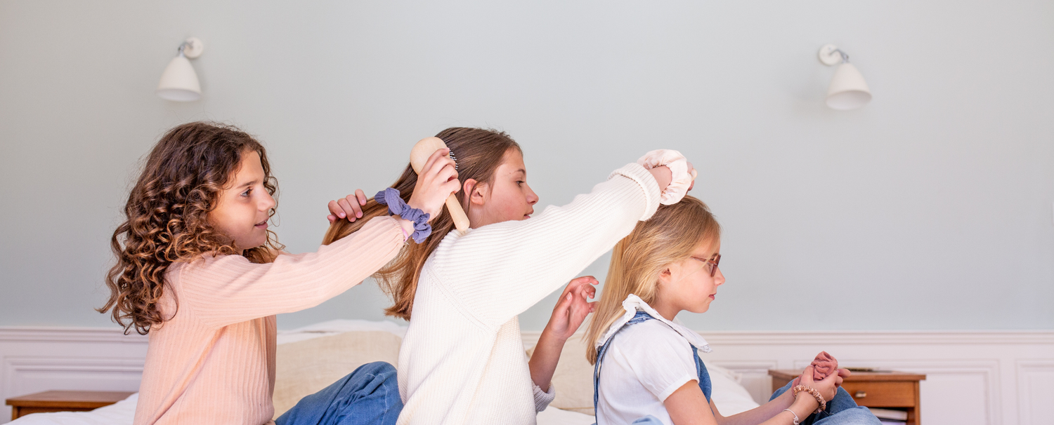 Petites filles se brossant les cheveux avec des brosses à cheveux de la marque Bachca sur un lit à la queue.