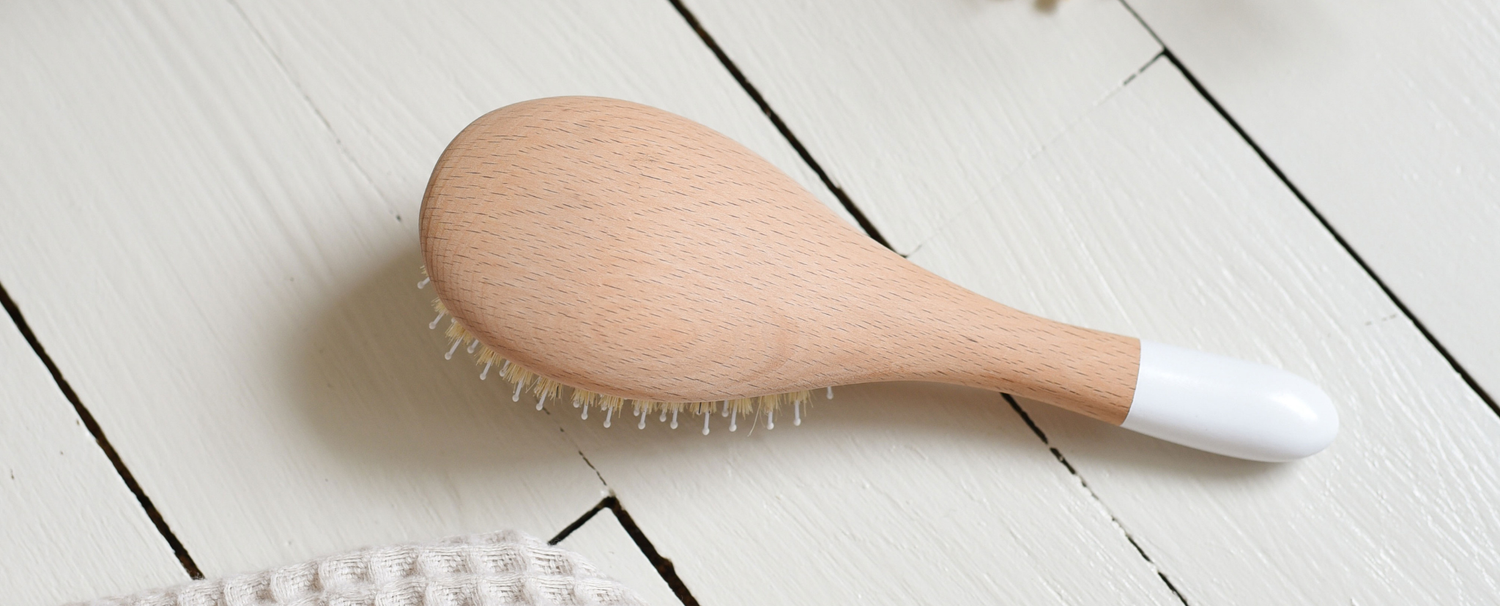 Brosse démêlage et brillance de la marque Bachca de dos posée sur du parquet blanc. 