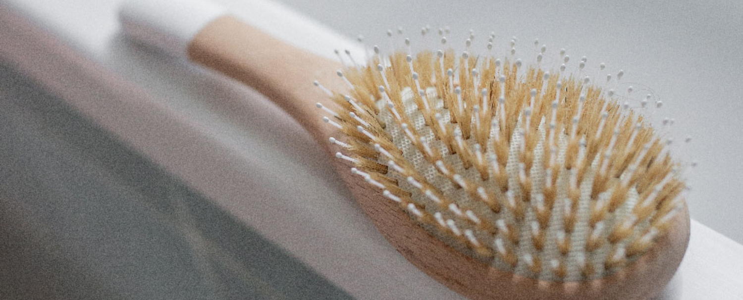 Brosse à cheveux démêlage et brillance de la marque bachca posée sur le rebord d'une baignoire. 