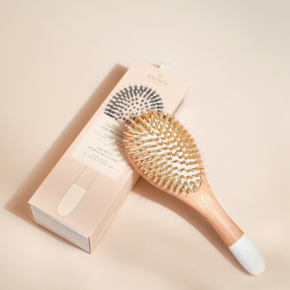 Brosse démêlante et brillance Bachca en bois de hêtre avec picots en nylon et poils de sanglier, présentée avec son coffret rose poudré élégant.