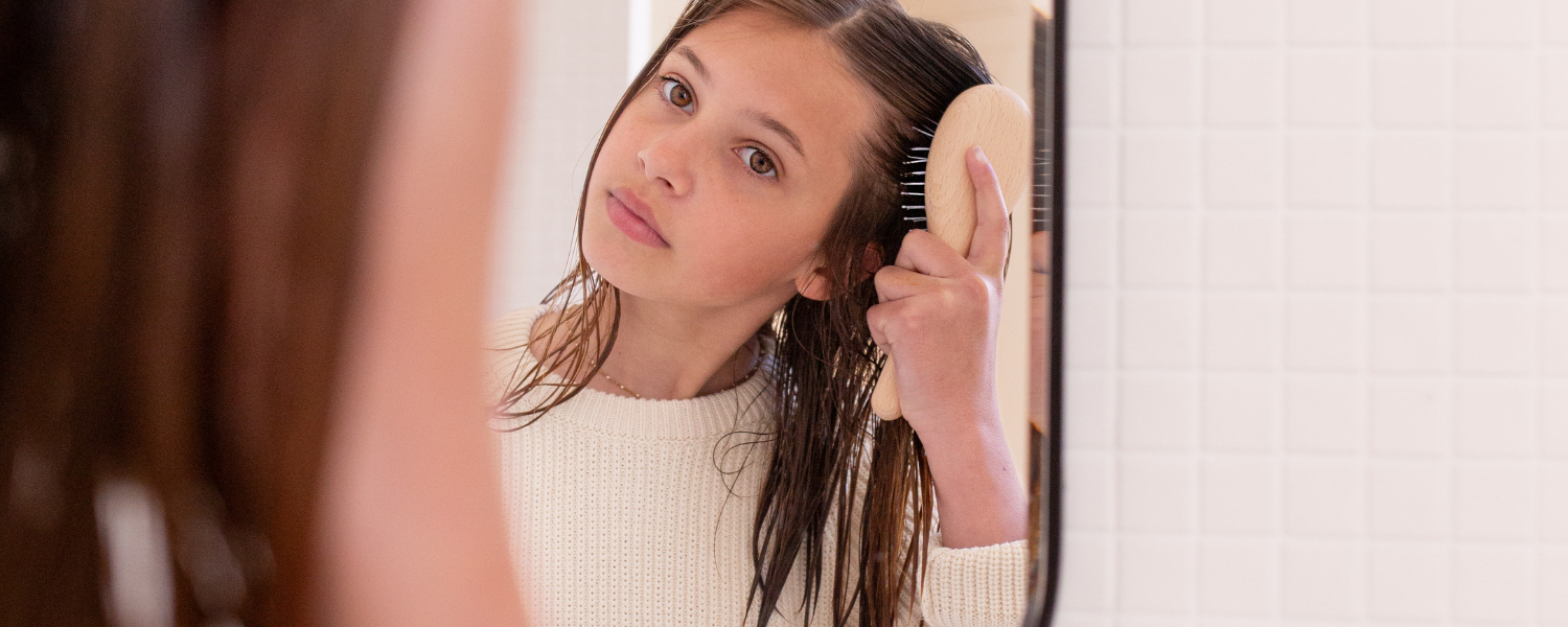 Jeune fille qui se brosse les cheveux devant un miroir avec sa brosse à cheveux Bachca.