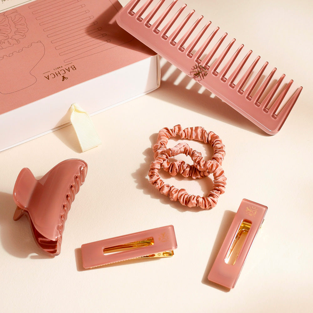Coffret Les Pépites bois de rose Bachca avec peigne large en acétate, pince cheveux assortie, deux chouchous en tissu et deux barrettes rectangulaires, élégamment disposés sur leur boîte rose.