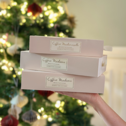 Photo lifestyle, trois coffrets de la marque Bachca sont présents, on peut voir un sapin et des décorations de noël en arrière plan.