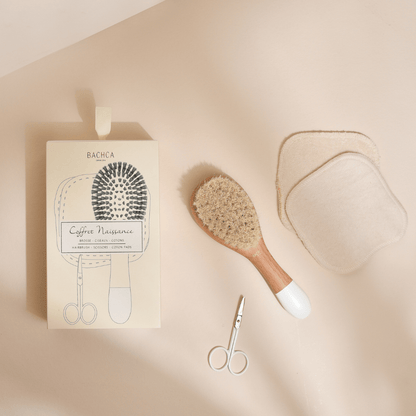 Coffret naissance Bachca, on peut voir la boîte du coffret, la brosse à cheveux nourrisson, des ciseaux bébé ainsi qu&