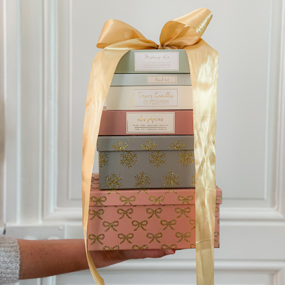 Photo de coffrets accessoires de la marque Bachca, sur un fond blanc avec moulures, un gros noeud emballe les coffrets.