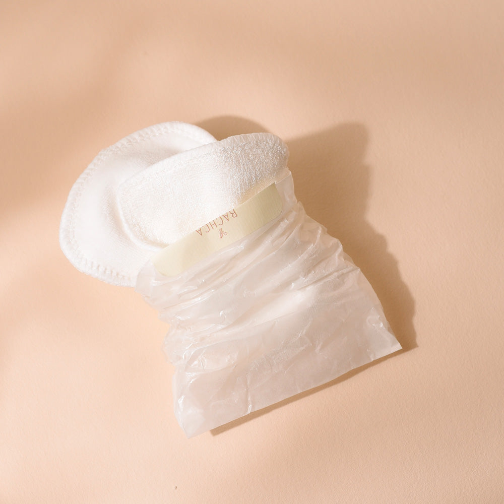 Lot de deux cotons démaquillants lavables Bachca en tissu blanc, présentés dans un petit sachet transparent, photographiés sur une surface beige.