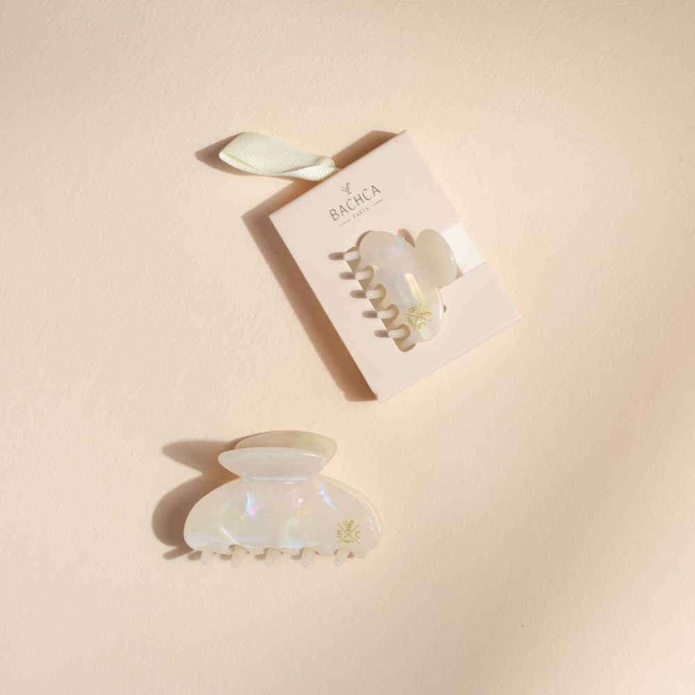 Deux pinces à cheveux effet nacre Bachca, l’une présentée sur son packaging rose avec ruban, l’autre posée à plat sur fond beige.