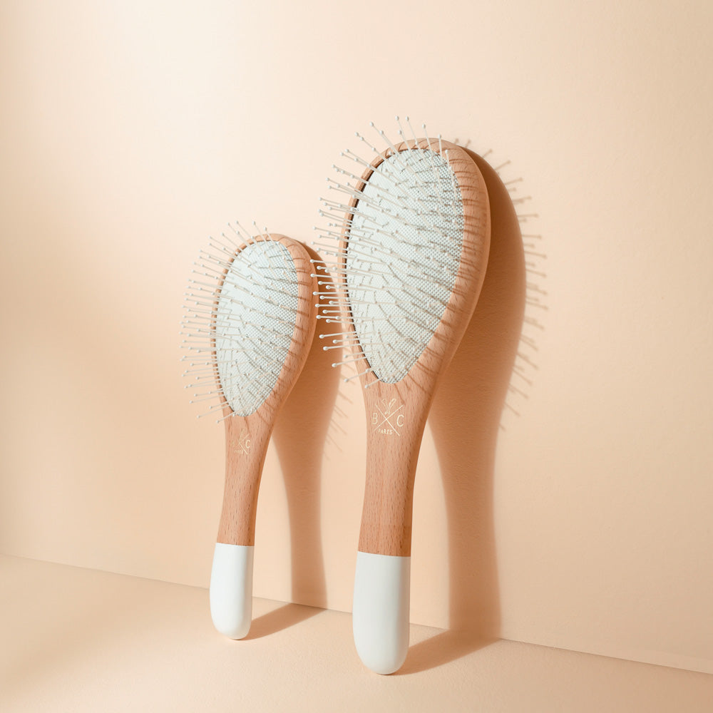 Grande et petite brosses Bachca assorties, en bois naturel et blanc, avec picots nylon, posées côte à côte sur fond beige.