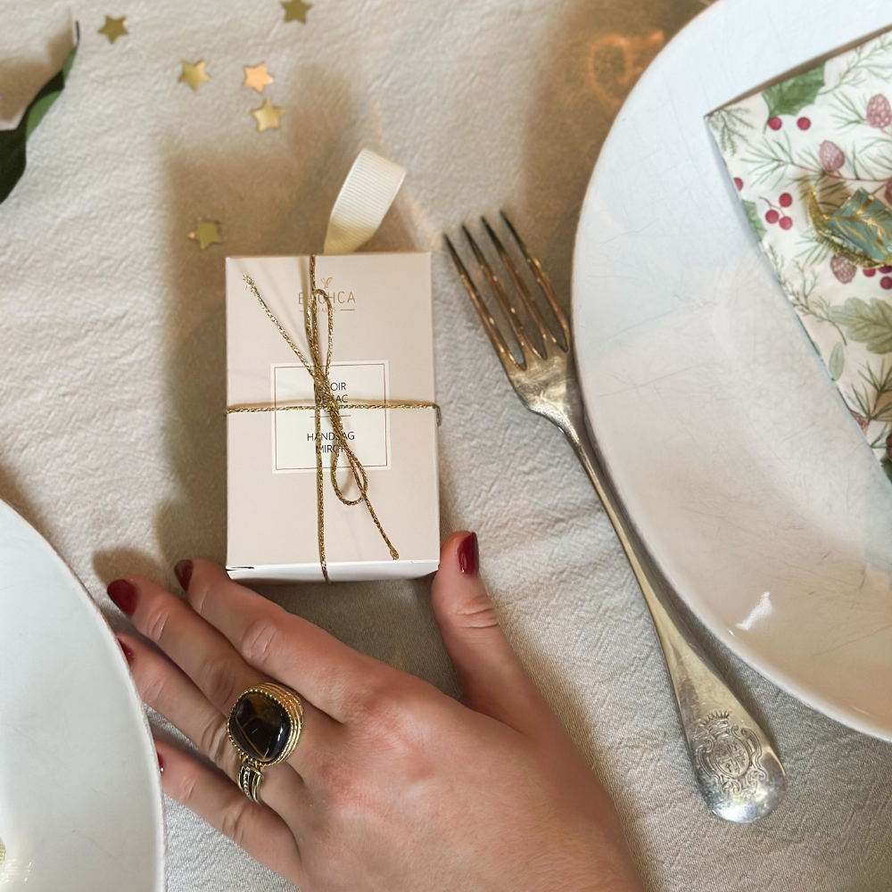 On peut apercevoir le miroir de poche de la marque Bachca emballé et présenté sur une table à manger festive.