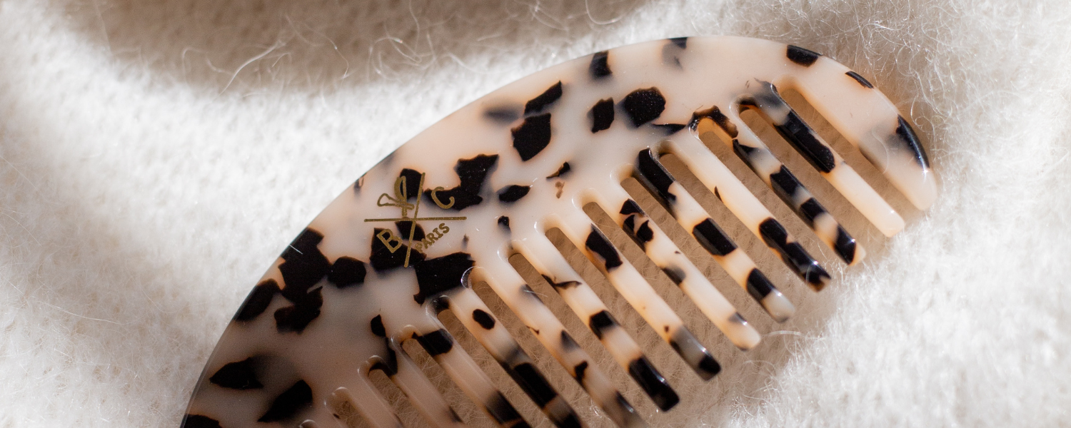 Un peigne en écaille de la marque Bachca est posé sur une maille blanche, on peut apercevoir tout les détails de l'écaille.