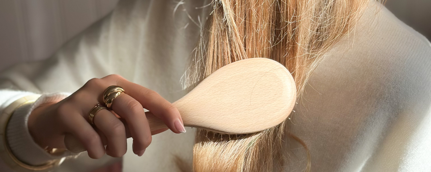 Femme brossant ses cheveux blonds avec une brosse à cheveux en bois de la marque Bachca.