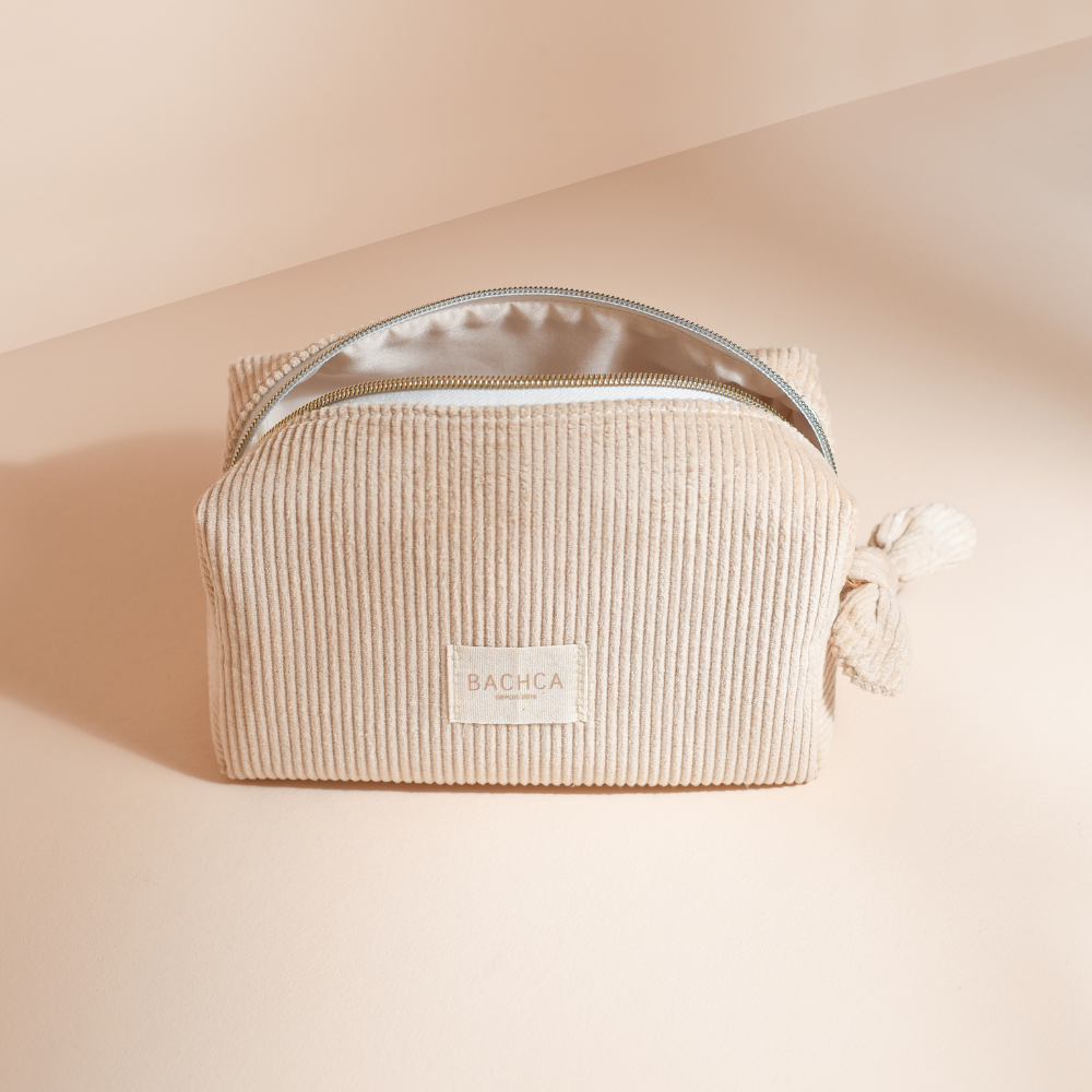 Trousse de maquillage BACHCA en velours beige ouverte, fond crème et lumière naturelle douce.