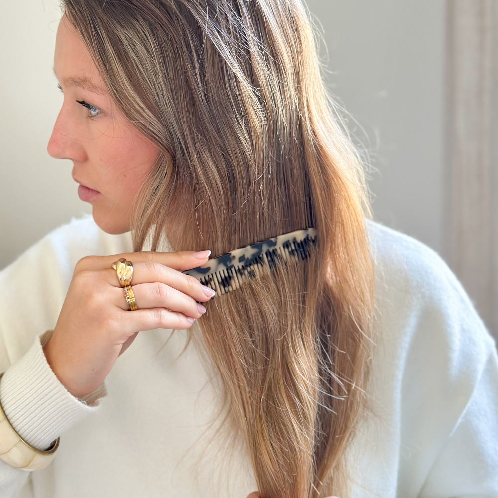 Jeune femme blonde qui se démêle les cheveux à l'aide d'un peigne pour cheveux fins écaille de la marque Bachca. 