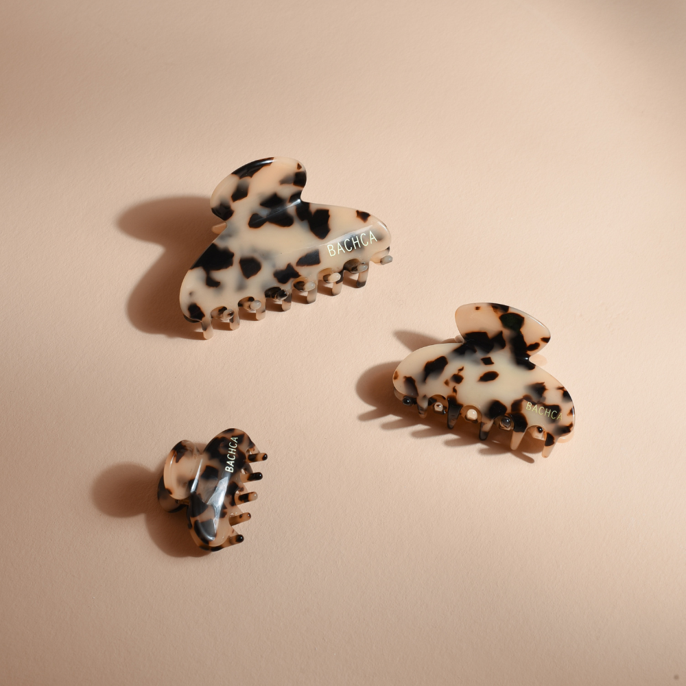 Trois pinces à cheveux écailles de la marque Bachca sur fond studio rose poudré.