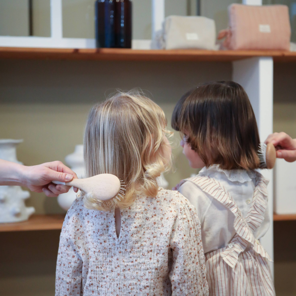 Deux fillettes sont de dos elles se font respectivement brosser les cheveux avec des brosses Bachca.
