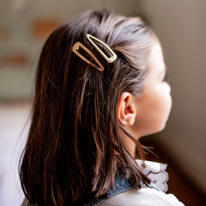 Petite fille portant deux barrettes Bachca en métal doré et ivoire, idéales pour attacher les cheveux avec élégance et simplicité.