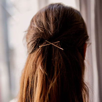 Cheveux attachés à l’arrière avec deux pinces guiches dorées Bachca croisées, accessoire discret et élégant pour maintenir les mèches en toute simplicité.