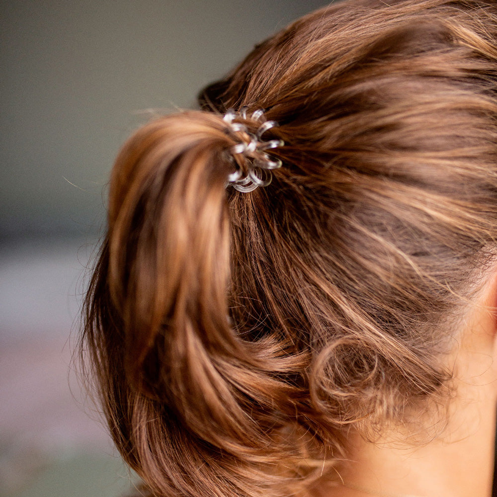 Queue-de-cheval attachée avec un élastique cheveux transparent Bachca, discret et sans trace pour un maintien confortable et invisible.