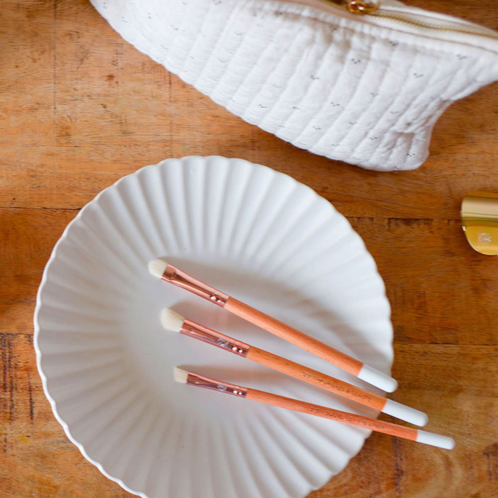 Trois pinceaux yeux Bachca avec manche en bois et embout blanc, posés sur une assiette blanche en céramique, accessoire maquillage.